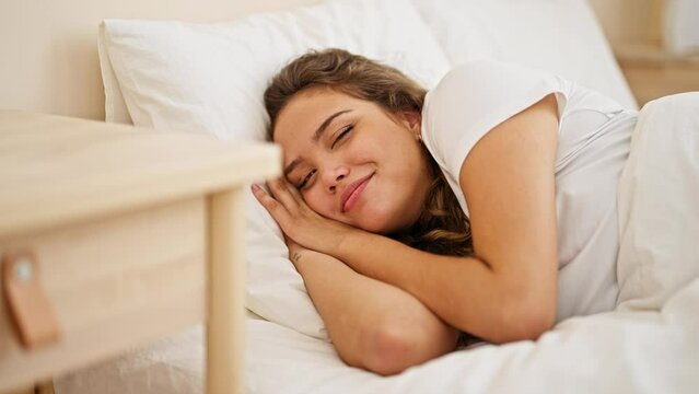 Young beautiful hispanic woman sleeping lying on bed waking up at bedroom