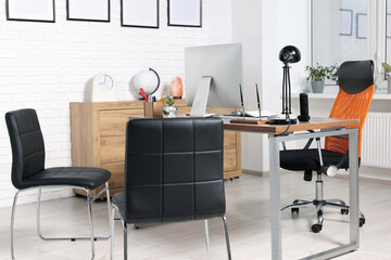 Stylish director's workplace with comfortable desk, computer and chairs for visitors in office....