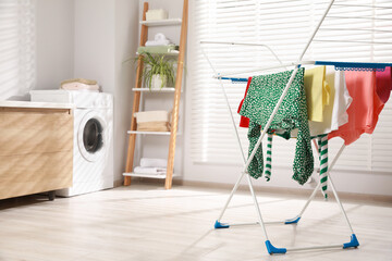 Different apparel drying on clothes airer in bathroom, space for text