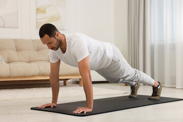 Naklejka premium Man doing morning exercise on fitness mat at home