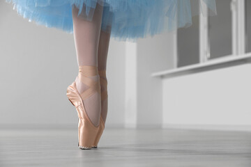 Ballerina in pointe shoes and light blue skirt dancing indoors, closeup. Space for text