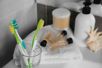 Colorful toothbrushes in glass holder on table indoors