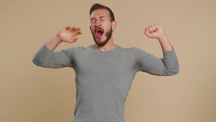 Tired overworked young lebanese man yawning sleepy inattentive feeling somnolent lazy bored gaping suffering from lack of sleep. Exhausted middle eastern guy isolated on studio beige background indoor