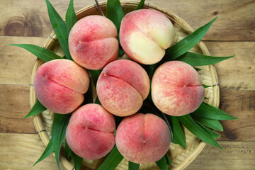 Peaches with leaves on the wooden table, Fresh Peach in wooden basket on wooden Background.