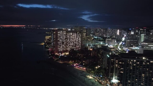Scenic illuminated Honolulu skyline at sunset. Aerial Oahu city at night scene. Beautiful urban landscape of coastal bay city at dusk. City lights on Hawaiian island. Downtown Waikiki beach at night