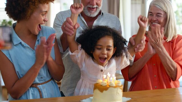 Father takes photo as multi-generation family celebrate granddaughter's birthday at home with cake - shot in slow motion
