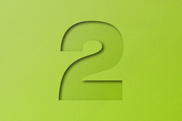 White paper type paper alphabet number 2 isolated on green background.