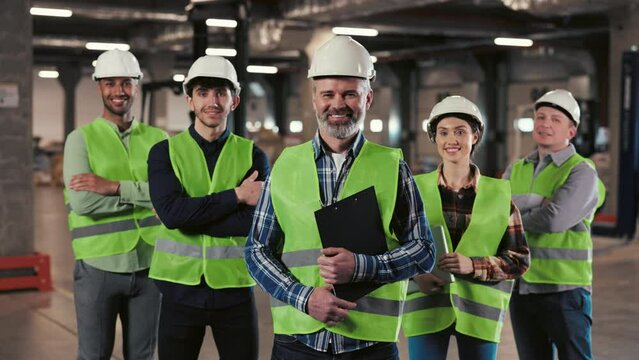 A Group of Warehouse Workers Stands in a Large Distribution Center with their Arms Crossed. Portrait of the Workers. People Looking at the Camera with Smile. Logistic. Distribution