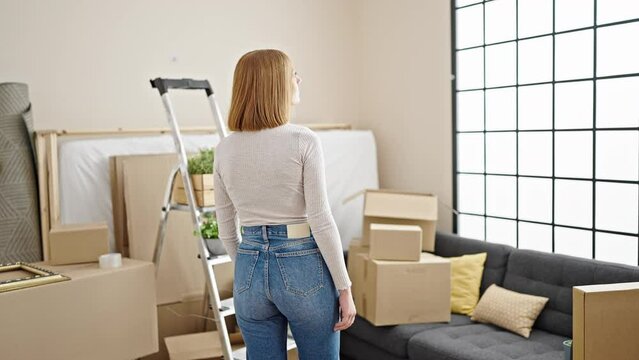 Young blonde woman standing backwards looking around at new home