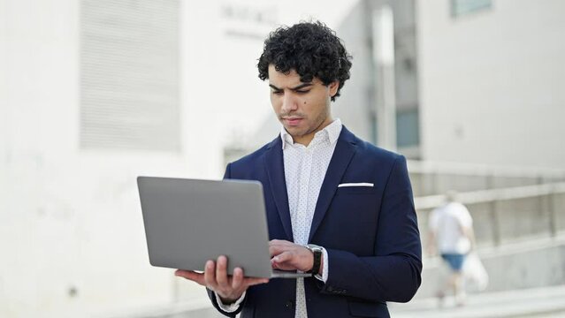Young latin man business worker using laptop at street