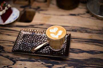 Hot latte art coffee on wood table with flower texture