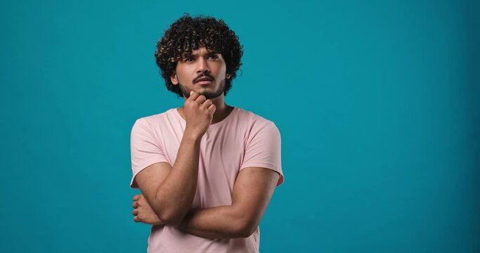 Pleased thinkful indian man is raising-up his finger while coming up with an idea standing isolated over blue studio background