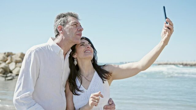Senior man and woman couple smiling confident make selfie by camera at seaside