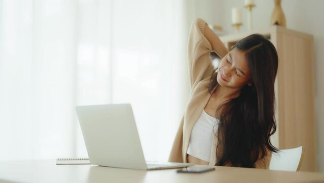Office syndrome concept. Young asian woman feeling pain in neck and shoulder after working on computer laptop for a long time. She stretches to relax her muscles