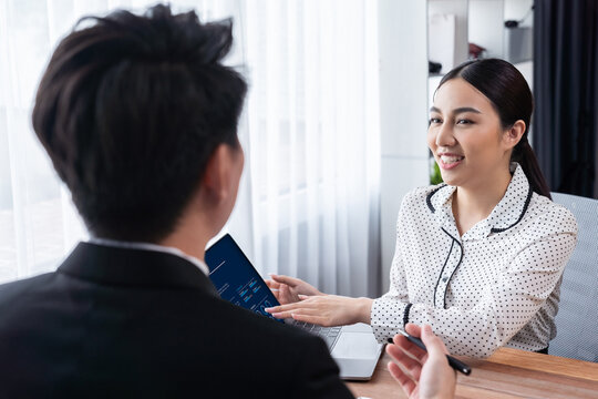 Conversational job interview between interviewer and candidate. Asian female job applicant present her performance and qualification by digital resume on laptop and CV paper to HR manager. Jubilant