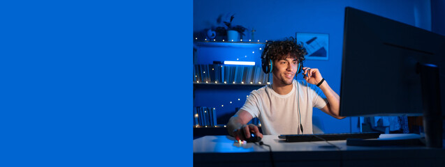 Positive arabic guy gamer streams game on computer and looks smiling at the camera. Smiling gamer playing video games. Copy space © Andrii Lysenko