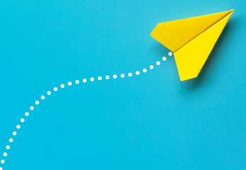 Top view of yellow paper airplane on blue background. Air transport and copy space.