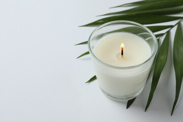 Obraz na płótnie Canvas Beautiful aromatic candle with palm leaf isolated on white background. SPA composition