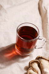 Natural medicine, reduce stress and improve immunity concept. Mushroom hot drink. Tea in glass mug with mushrooms on textile background. Copy space. 