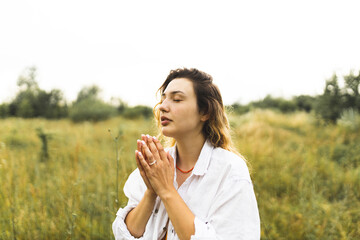 A girl prays to God in a field. The girl is in the field, raises her hands to the sky and prays to the Lord. Inspired by fervent female prayer. Spiritual growth. Faith and spirituality.