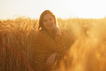 Close-up portrait of beautiful young woman in a countryside field. Female face in the rays of sunset. Freedome and happiness concept.
