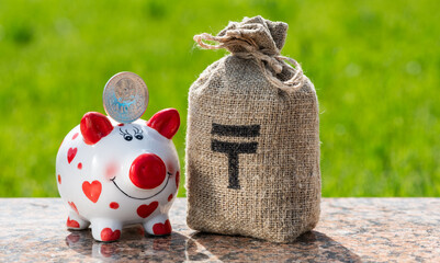 Piggy bank, 100 Kazakhstani tenge coin and money bag with tenge symbol