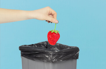 Throw strawberries into the trash can, strawberries in hand in front of the trash can, food throw...