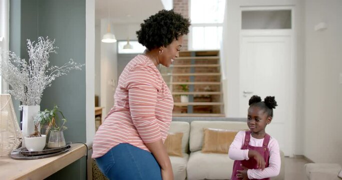 Happy african american mother and daughter dancing at home, slow motion
