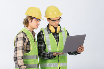 Two young Asian engineers in light green coats and yellow hats inspecting work on laptops. Focus hard work together on white background