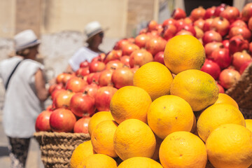 Oranges and pomegranates at a street market with customers in blurred background