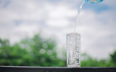 Water from bottle pouring into glass on table, bokeh background. clean water for a good health....