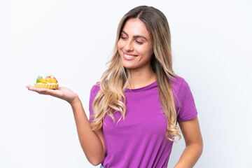 Young pretty Uruguayan woman holding a tartlet isolated on white background with happy expression