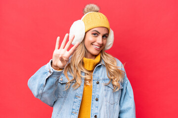 Young pretty Uruguayan woman wearing winter muffs isolated on red background background happy and counting four with fingers