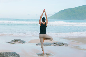 In a blissful coastal retreat, a woman practices restorative yoga on the beach, rejuvenating her spirit and finding solace in the serene atmosphere.
