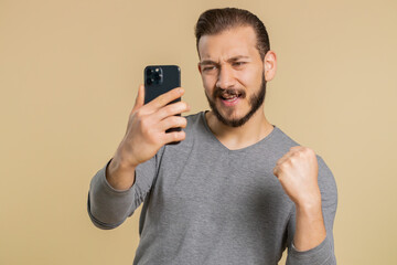 Happy excited joyful lebanese man in long sleeve use smartphone typing browsing shouting say wow yes found out great big win, good news, lottery goal achievemen, celebrating success, winning game