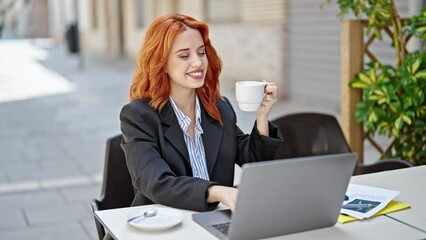 Young redhead woman business worker using laptop drinking coffee dancing at coffee shop terrace