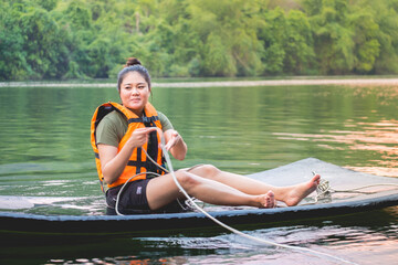 A tourist chubby girl wear life jacket smiling on pontoon in Kanchanaburi river with natural therapy relax in vacation holiday in thailand concept