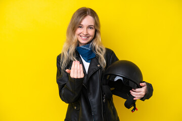 Blonde English young girl with a motorcycle helmet isolated on yellow background inviting to come...