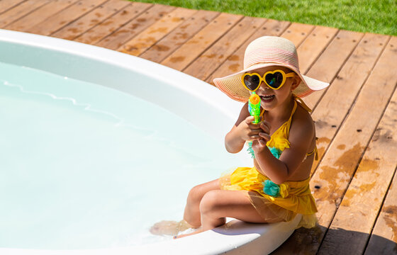 A child plays in the pool with a water gun. Selective focus.