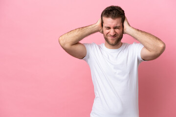 Fototapeta na wymiar Young caucasian man isolated on pink background frustrated and covering ears