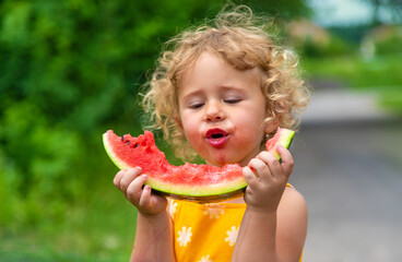 A child eats watermelon in the park. Selective focus.