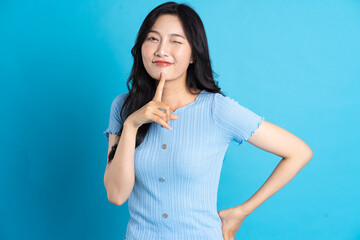 Portrait of a happy smiling asian girl posing on a blue background