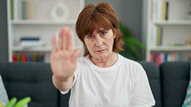 Middle age woman doing stop gesture with hand home