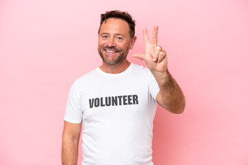 Middle age volunteer man isolated on pink background isolated on pink background happy and counting three with fingers