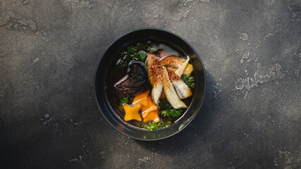Asian food. Soup with mushrooms, seafood and eggs in a stylish plate. Restaurant serving.