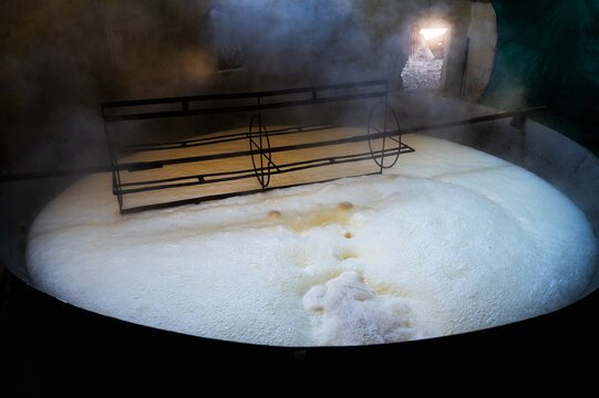 Sugarcane Jaggery in making by boiling sugarcane juice to make concentration, frothing at upper layer in big utensils and big circular stirrer.