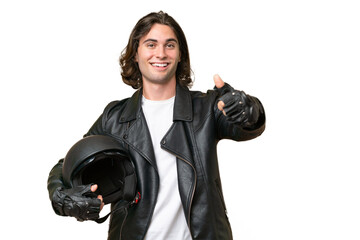 Young handsome man with a motorcycle helmet isolated on green chroma background giving a thumbs up gesture