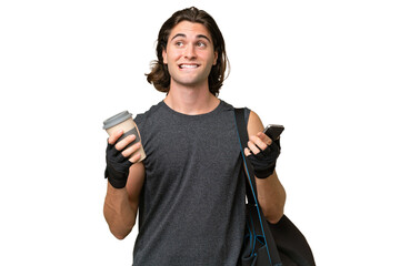 Young sport handsome man isolated on green chroma background holding coffee to take away and a mobile while thinking something