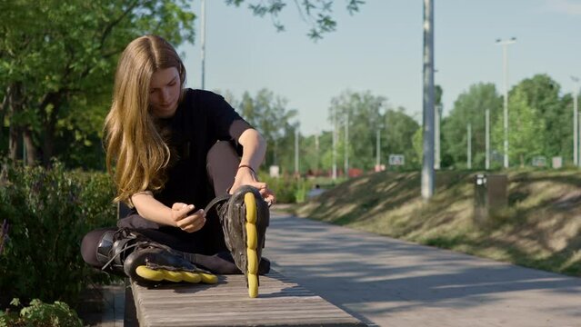 young beautiful girl in park tying laces on roller skates before skating workout active lifestyle hobby