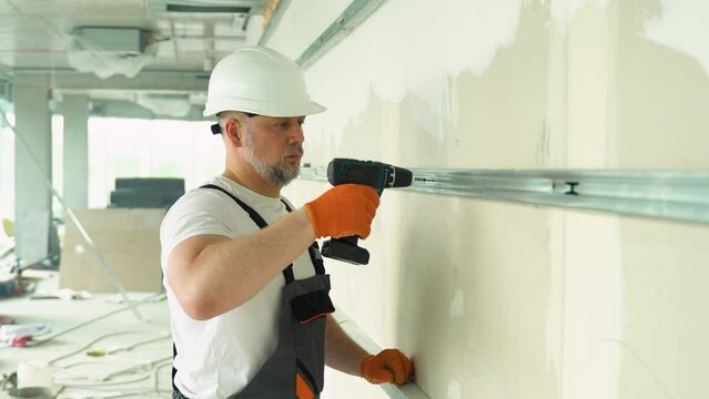 Worker builder installs plasterboard drywall at a construction site